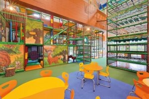 Softplayanlage im Indoorspielplatz Tannis Kinderparadies im Hintergrund und Bistrotische im Vordergrund