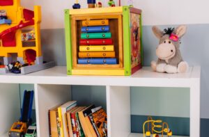 Regal im Spielzimmer des Café Rösternest in Illertissen mit Spielwürfel, Kuscheltier und Autorennbahn