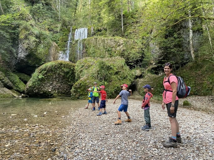 Kinder spielen am Wasserfall und werfen Steine im Steigbachtobel beim Immenstadt