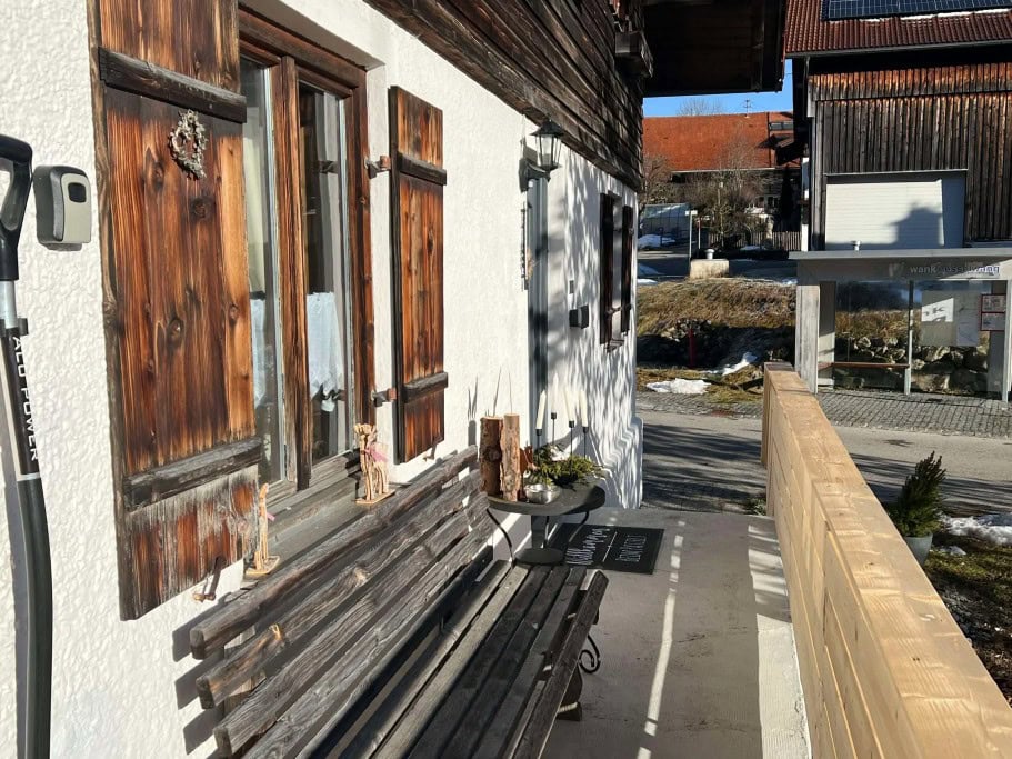 Eingangsbereich aussen vor de Ferienhaus beim Patzelt in Nesselwang mit Sitzbank und urigen Fensterläden