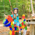 Kleiner Junge fährt mit Helm auf einem Reitpferd im Abenteuerpark in Immenstaad am Bodensee